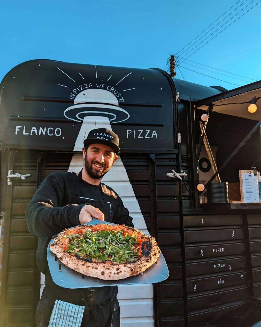 Eliot serving pizza at the Flanco Pizza oven